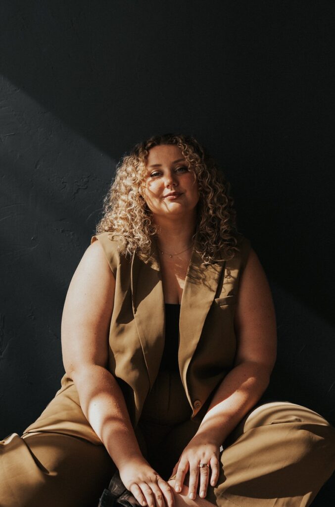 A person sitting on the floor smiling with one leg bent and the other leg straight